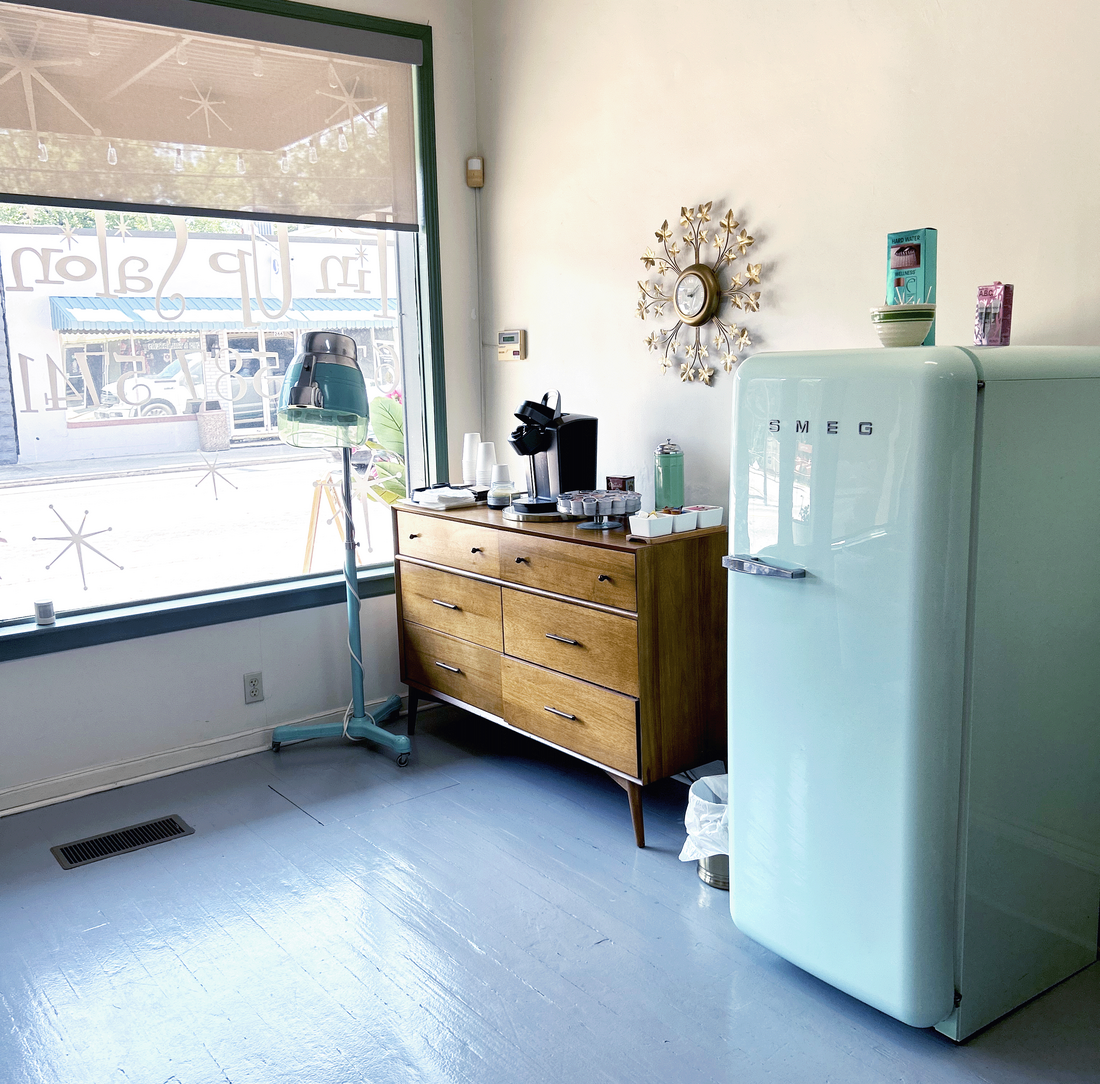 Vintage aqua blue Smeg fridge and vintage aqua blue hair dryer by a coffee station 